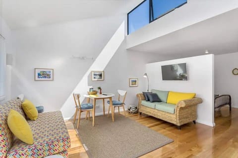 Experience relaxation in the cozy living room, complete with comfortable seating and a wall-mounted smart TV. A small dining table caters to meals at home.