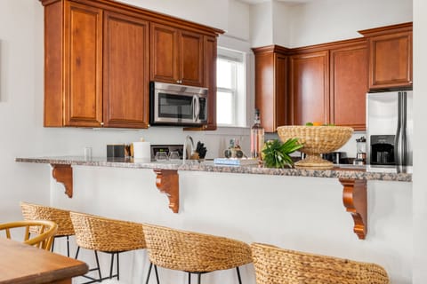 Kitchen features a countertop breakfast bar with seats and modern appliances.
