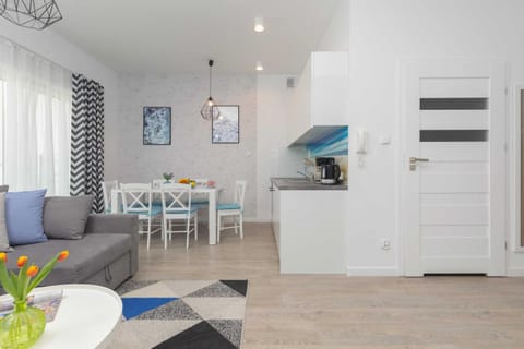 A modern open-concept living area with light-colored flooring, a sofa, and stylish curtains. The combination of blue and gray creates a calm atmosphere.
