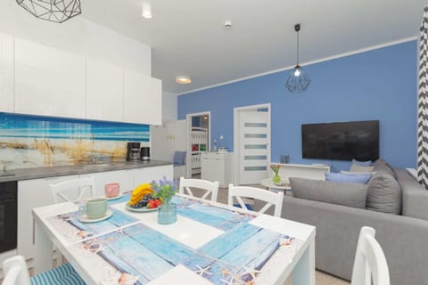 A modern kitchenette with clean white cabinets and a stylish backsplash seamlessly connects to the dining area. The elegant table, set for meals, complements the space, making it both practical and inviting.