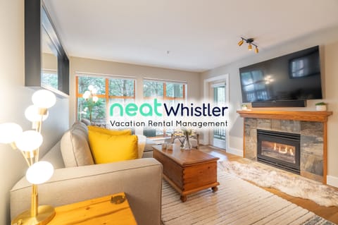 Living room with 60" TV, gas fireplace, and patio with furniture and BBQ.