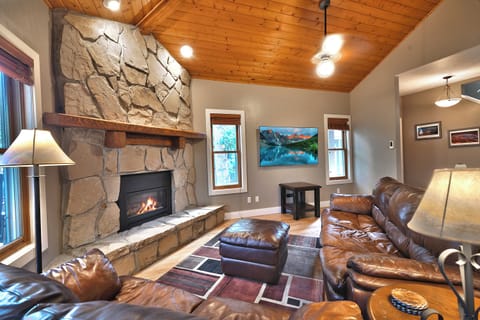 Living room with feature rock fireplace wall, leather couches and wall mounted flat screen TV