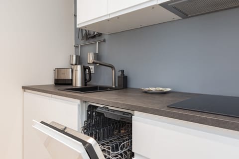 A modern kitchen with a long countertop, sleek appliances, and a view of the living area.