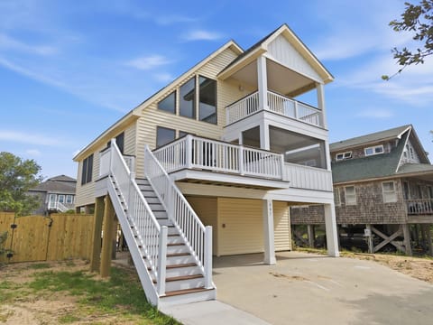 Raised coastal home with sunny decks, balcony, and covered parking