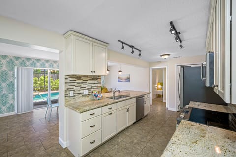 Kitchen overlooks dining and crystal clear pool 