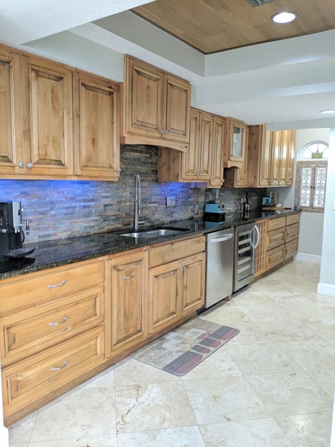 Kitchen with granite countertops, wine fridge and stainless steel appliances.