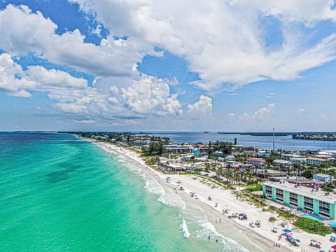 Aerial view of the coastline showing turquoise Gulf waters, sandy beach, and surrounding island community