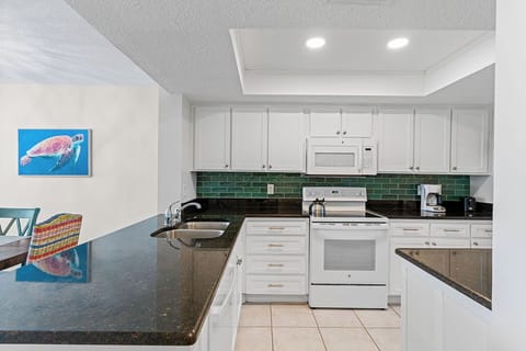 Your fully equipped kitchen awaits with granite counters, white cabinets, and colorful tile backsplash—perfect for preparing meals during your stay.