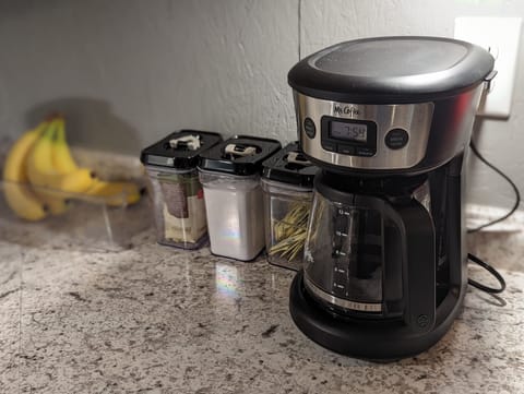 Coffee pot, toaster, and new dishes are ready for guests. 