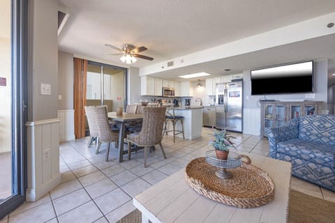 Dining area with woven chairs, a modern kitchen featuring granite countertops, and a cozy seating nook with a TV