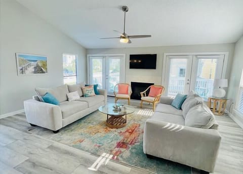 Sink into comfort in your spacious living room where modern coastal elegance meets relaxation with bright windows and cozy seating.