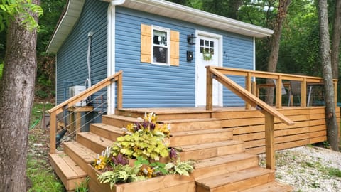 The humble blue tiny house meets you with its wrap around deck.