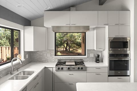 Cook like a chef in this bright, modern kitchen featuring high-end appliances, sleek countertops, and beautiful forest views right from the window—perfect for creating meals with a side of serenity.