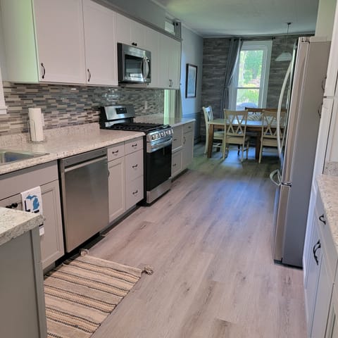 Kitchen view toward dining room with new fridge, range, dishwasher, microwave.