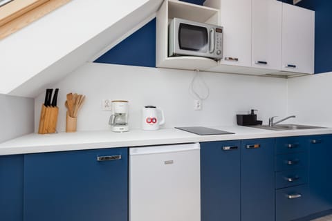 A kitchenette with a microwave, sink, and storage, designed for easy meal preparation.
