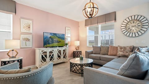 Chic living room with soft pastel accents, cozy seating, and TV!