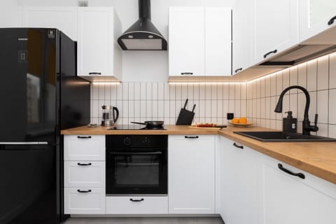 Fully equipped kitchen featuring black and white cabinetry, wooden countertops, and modern appliances.