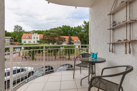 Balcony with a small seating area and a scenic view of the green surroundings.

