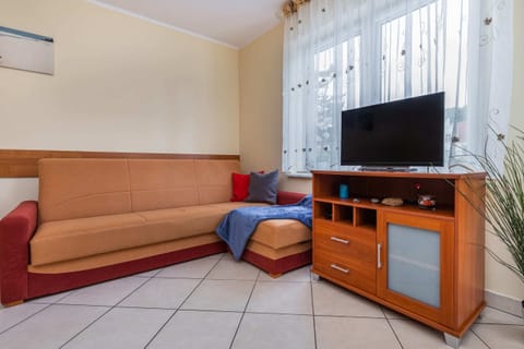 Living room with a cozy corner sofa, TV, and a bright window for natural light.
