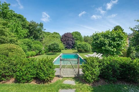 Door leading to pool and sun beds surrounded by lots of foliage
