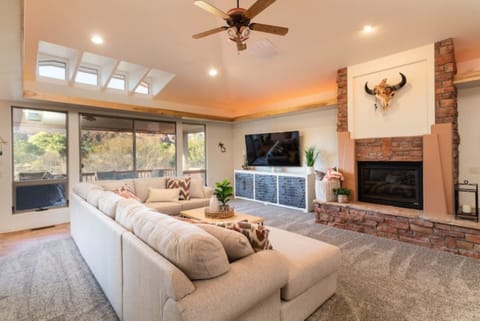 Main living area w/ stunning views of Sedona, a 75" smart TV and gas fire place