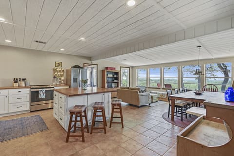 As you leave living area 2 you see the kitchen on the left, the dining table in front of you, and living room one with seating positioned to take advantage of the beautiful views afforded by the home.
