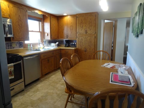 Kitchen with dining table, dishwasher, stove, fridge, microwave, Keurig and regular coffee pot, lots of cupboard space, dishes, pots, pans, silverware.