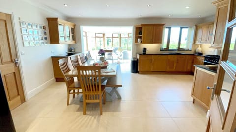 The spacious kitchen - dining area with seating for upto 11, leading from the large living room and into the bright sunroom area. | Llwyn Ysgaw, Cemaes