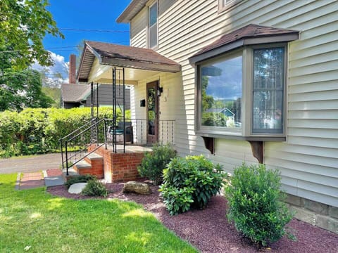 Front view of the house showcasing tidy landscaping, sunny windows, and a welcoming porch