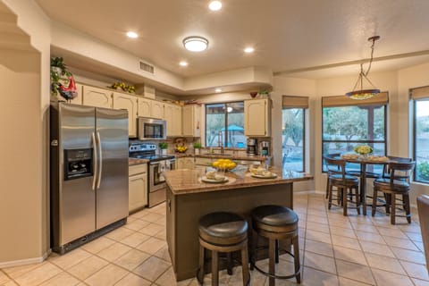 Spacious, well stocked kitchen with table and island seating plus backyard views.