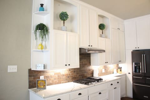 Luxurious Kitchen with white cabinets, quartz countertops and gas stove