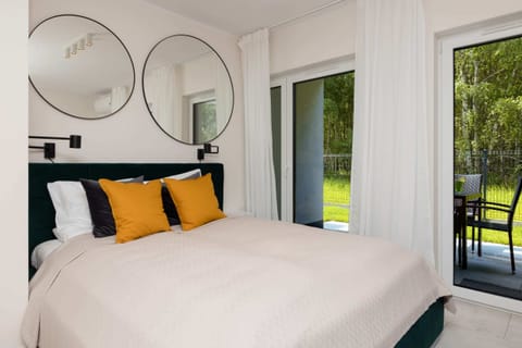 A bedroom with a large bed, yellow cushions, and a window with natural light