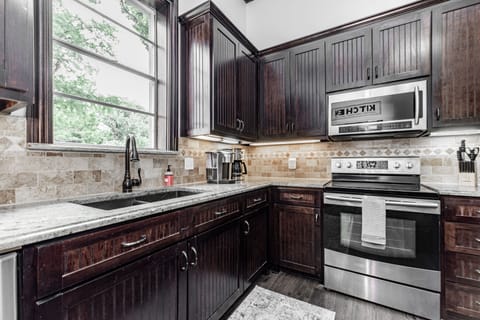 Kitchen with microwave, oven, stove top, and coffee maker.