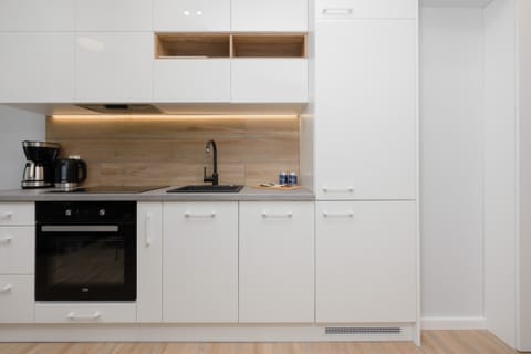 A sleek white kitchen with built-in cabinets, wooden countertops, and modern appliances. The design is minimal and clean.