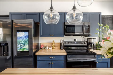Modern kitchen w/ sleek cabinets, stainless steel appliances & statement pendant lighting.