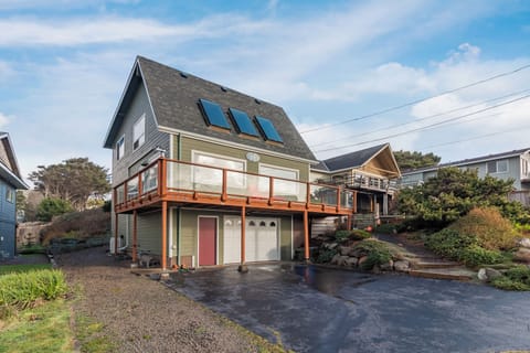 Coastal vacation home features modern design with wraparound deck and skylights in quiet residential neighborhood.