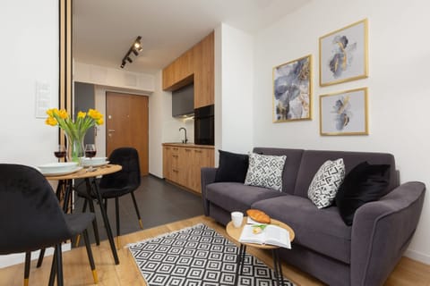 A cozy and modern living area with a fold-out gray sofa above which there are paintings hanging that add style to the room.