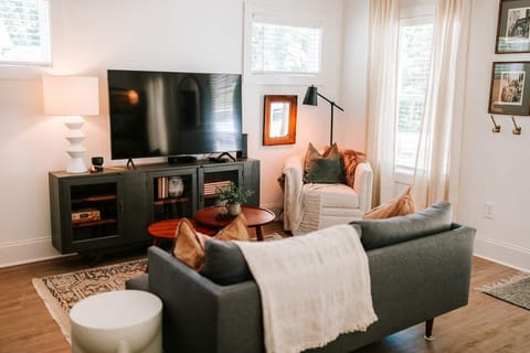 The stylish living room features a comfy sofa, a large HDTV with premium cable, a record player, and an assortment of books, making it the perfect room to gather with your group and enjoy some quality time together!
