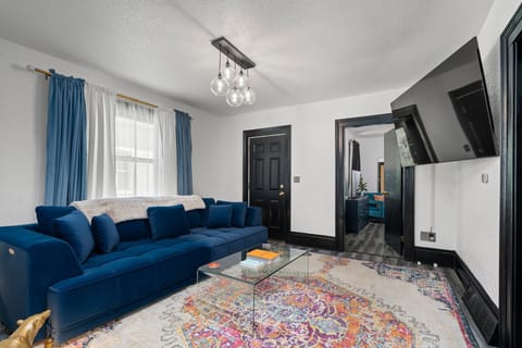Bright living room w/ plush blue sofa, colorful rug & wall-mounted TV for relaxed movie nights