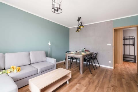 A modern living room with a gray sofa, a wooden coffee table, and a vibrant orange accent wall creating a cozy and inviting atmosphere.
