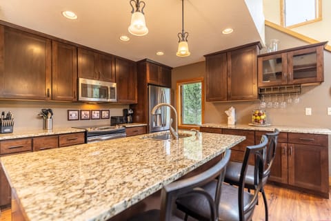 Full-sized kitchen featuring stainless steel appliances, granite countertops, kitchen island, and hardwood floors.