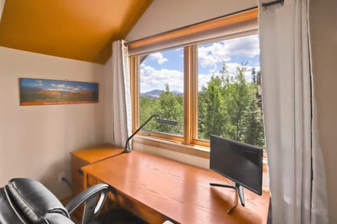 The dedicated work space featured in the master bedroom boasts a desk, lamp and a monitor as well as lovely nature views.