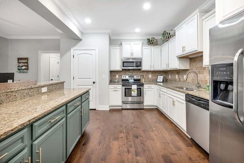 Kitchen with white and green cabinets, granite counters, stainless appliances