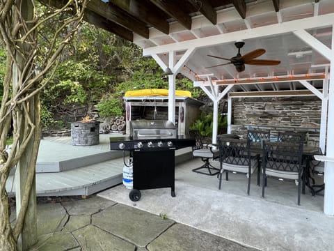 Outdoor covered patio with barbecue, fire pit, dining table, and bar.