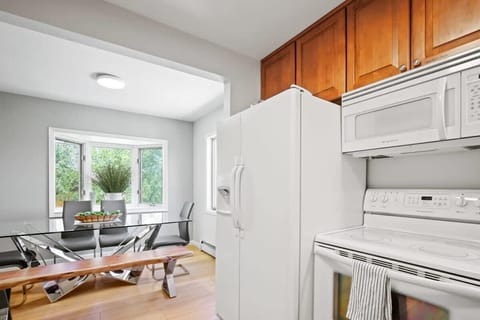 Just off of the kitchen, find the dining area that features a sleek, glass table with seating for eight and abundant natural light and mountain views thanks to the many windows that surround it.