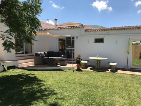 Garden area with corner sofa and round table with bench seats . 