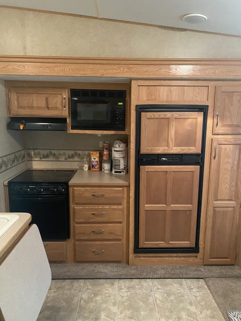 Kitchen with fridge, freezer, 3-burner stove, oven, microwave and coffee pot. 