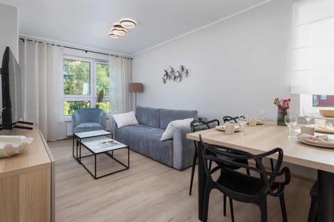 A cozy living room with a comfortable sofa, a modern coffee table, and a dining area in a bright open space.

