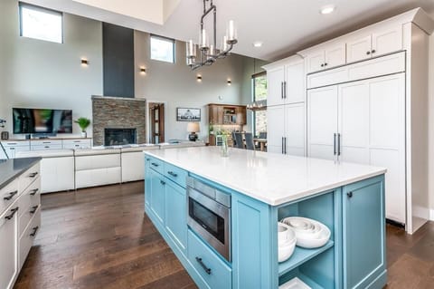 - Bold blue island anchors this dream kitchen with prep space and open shelving
- Built in microwave and sleek surfaces make meals easy and enjoyable
- Enjoy seamless sightlines to the fireplace and dining area while you cook

