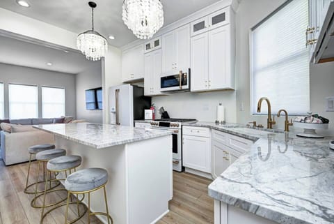 True chef's kitchen with white GE Cafe appliances including a gas oven range, a refrigerator/freezer, microwave, dishwasher, garbage disposal, and drinking water faucet.